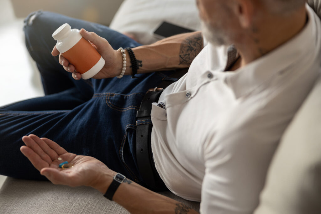 Male is examining a bottle of pills